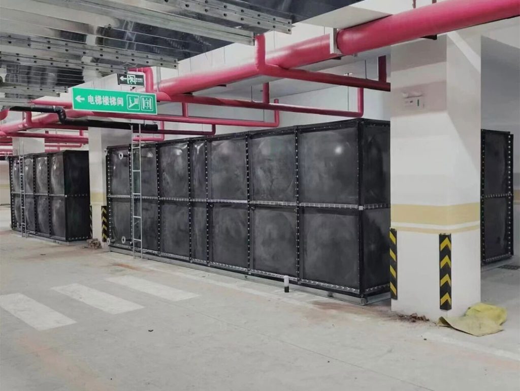 Workers assembling enamel steel water tank panels on-site with protective handling during installation.