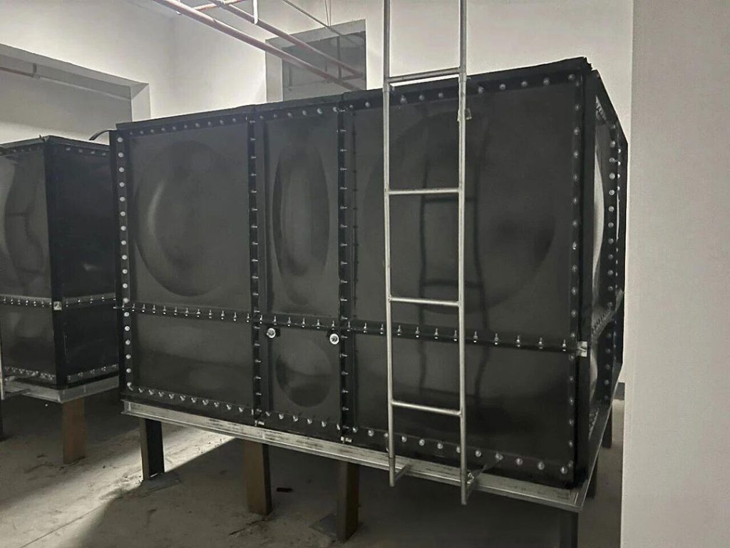 Modular enamel steel water tank installed for hospital drinking water storage with reinforced sectional panels.