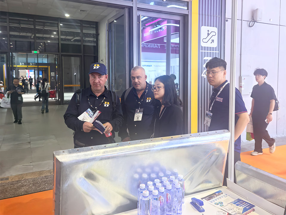 International visitors consult technical details of modular stainless steel water tanks.